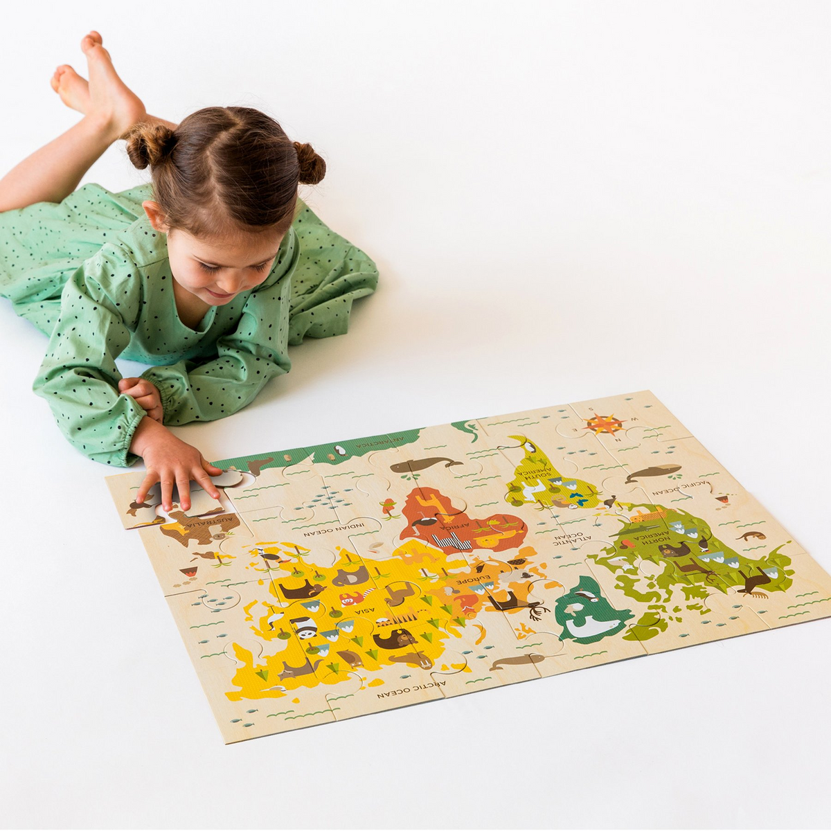 Fetiță care asamblează pe jos un puzzle de podea cu harta lumii de la JucariiAltfel.